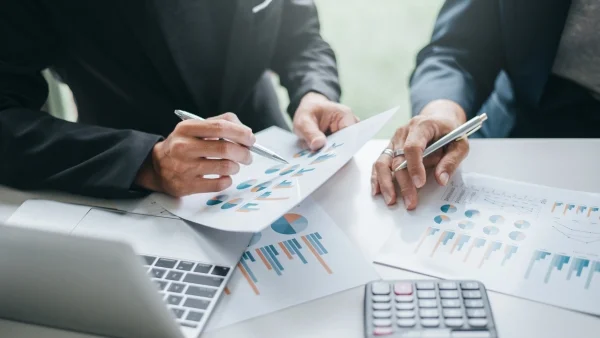 Zwei Personen vergleichen Finanzierungsunterlagen mit Diagrammen