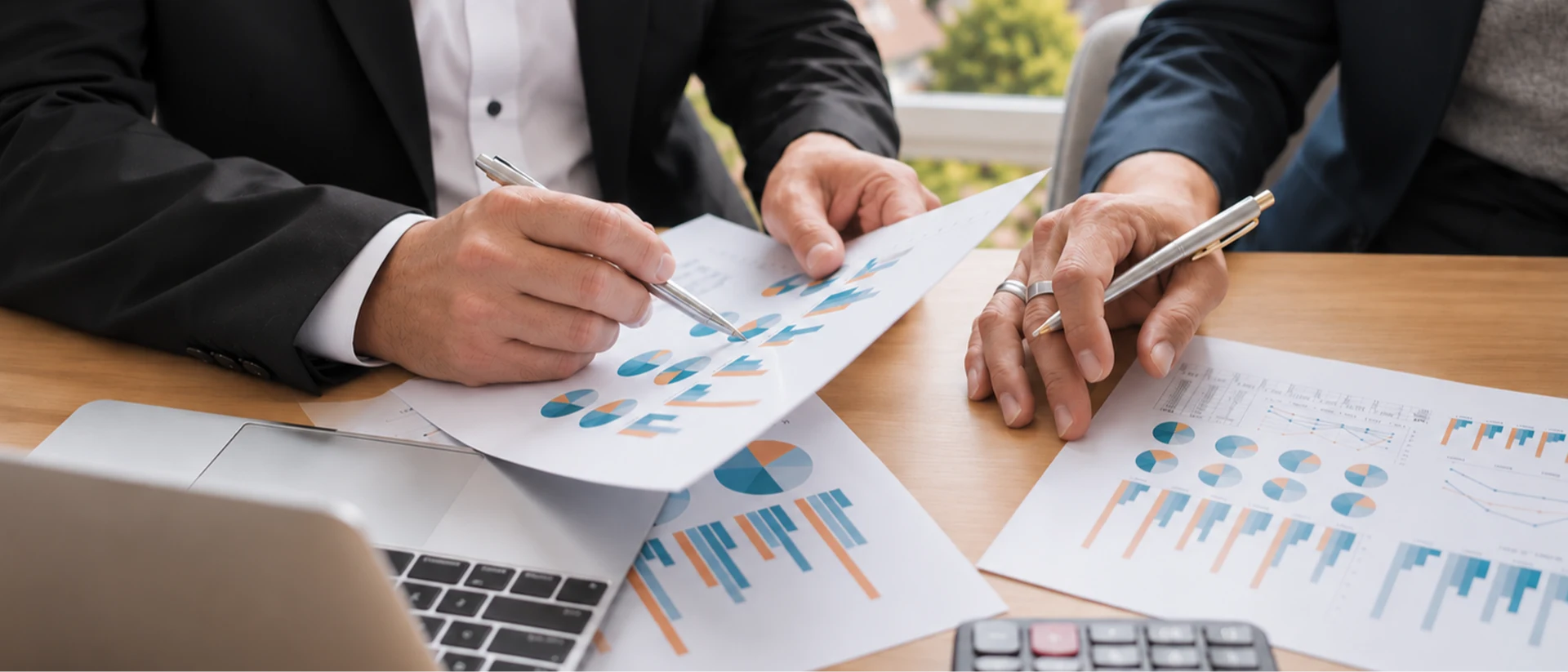 Zwei Finanzexperten analysieren gemeinsam Diagramme und Unterlagen am Schreibtisch und besprechen individuelle Finanzierungsmöglichkeiten für eine Baufinanzierung Bodensee.